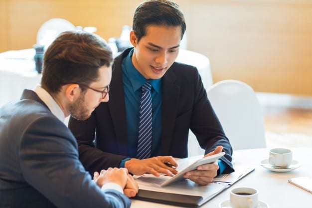 how to become a management consultant. Image shows two consultants discussing a business issue over coffee.