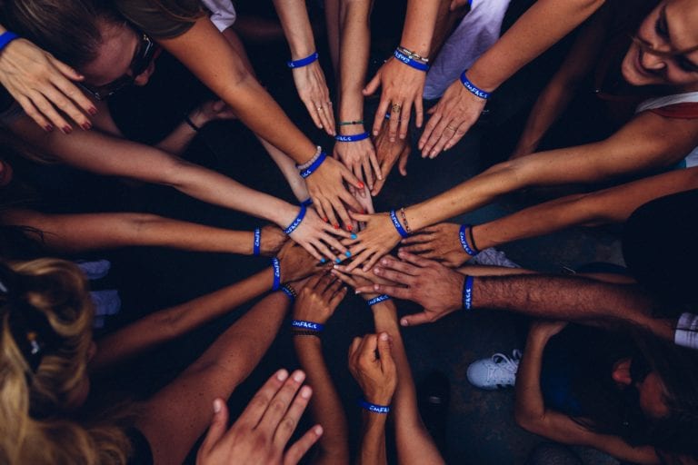 Case frameworks. Picture depicts 2 dozen hands all pulled in for a teamwork huddle.