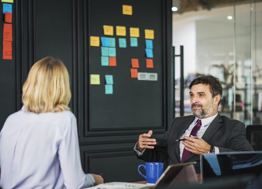 consulting behavioral interviews. Image depicts a man and a woman having a business conversation.
