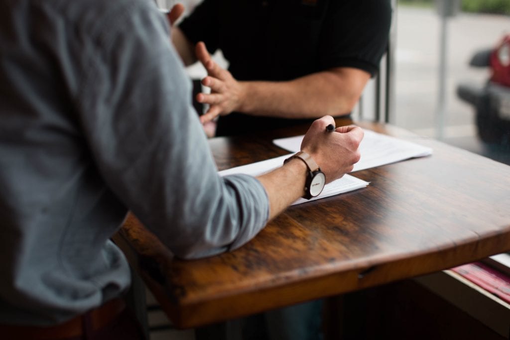 Questions to ask in a consulting interview. Image pictures 2 men discussing business.