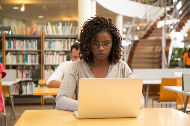 Bain online multiple choice test. Image shows a woman sitting at a desk working on her laptop.