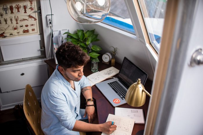 Case Interview Video Conference. This image shows a college student sitting at the desk in his dorm in front of a laptop, preparing for his virtual interview.