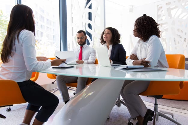 Questions to ask during informational interview consulting. Image shows a team of people meeting around a conference table.