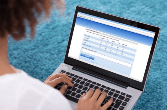 image shows a woman taking on online test such as the Oliver Wyman online test on a laptop computer