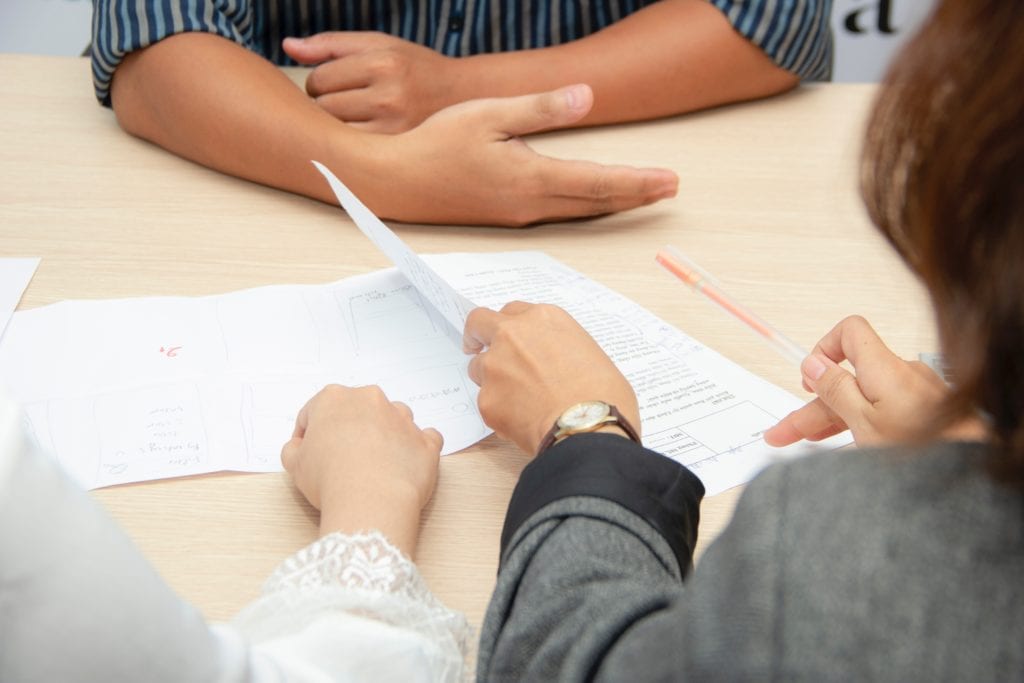 Bain final round experience interview. Picture shows 3 business people gathered around a conference table looking at papers.