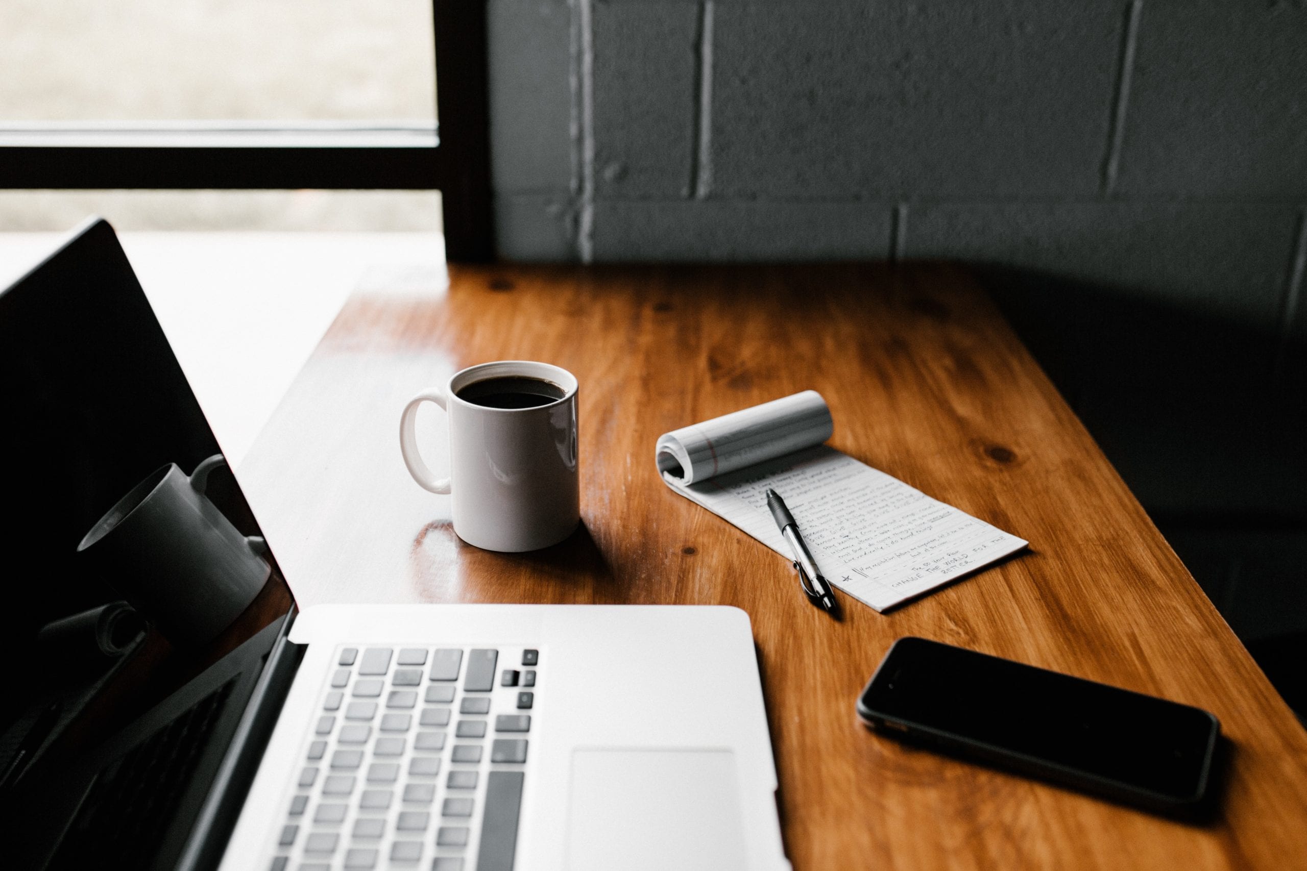 Virtual case interviews. This image shows a desk with a laptop, a notepad filled with notes and a mug of coffee waiting.